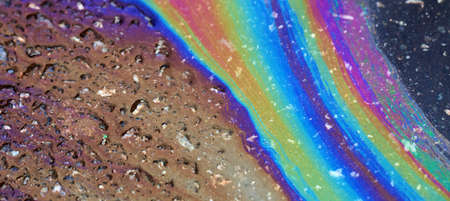 Bold multicolored spots on the asphalt. Water pollution by oil products.の写真素材
