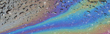 Bold multicolored spots on the asphalt. Water pollution by oil products.の写真素材