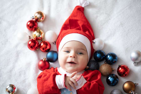 Toddler in a suit of Santa Claus with Christmas tree decorations.の写真素材