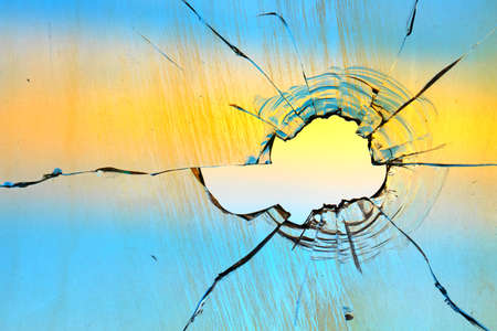 The war in Ukraine, the Russian invasion, bullet holes on the background of the Ukrainian flag. Cracks in the glassの写真素材