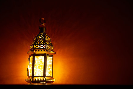 Ornamental Arabic lanter glowing at night .