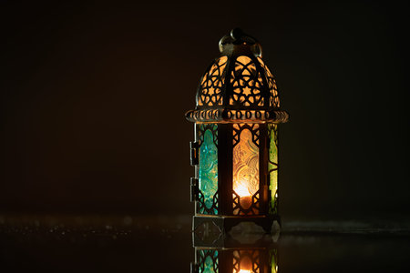 Ornamental Arabic lantern with burning candle glowing at night.