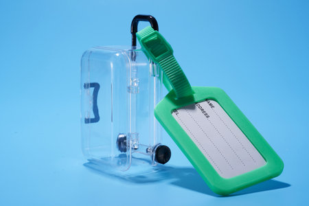transparent luggage and luggage tag against blue backgroundの写真素材