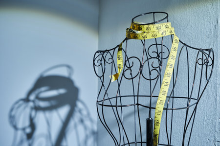 light spot on wire mannequin and tape measure  against gray backgroundの写真素材