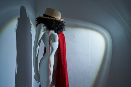 plastic human mannequin with alfro hairstyle and straw hat against gray backgroundの写真素材