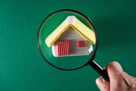 magnifying glass and small model house against green backgroundの写真素材