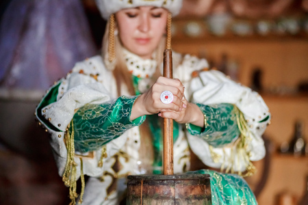 Young woman in traditional siberian dress producing butter from milk at home, inside the yurt.の写真素材