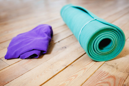 Mat for yoga rolled into a roll on the wooden floorの写真素材