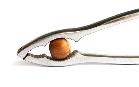 Metal nutcracker with a hazelnut isolated on a white backgroundの写真素材