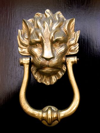 A brass door knocker in the shape of a lion's head on a black wooden doorの写真素材