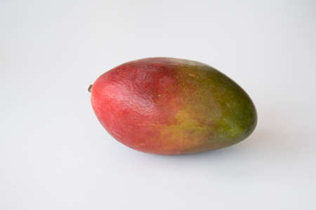 Tasty whole piece of mango fruit on a plain white backgroundの写真素材