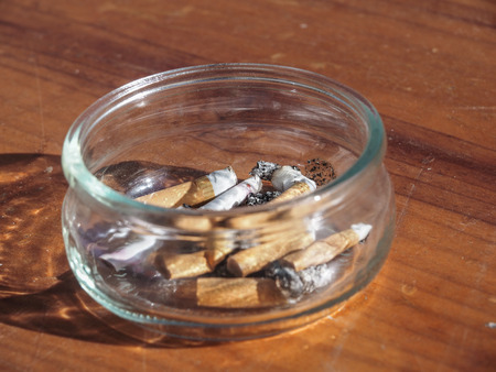closeup of a ashtray with cigarettes on a wooden tableの写真素材