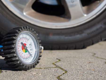 Closeup of a tire of a car and the scale of a compressor to measure air pressureの写真素材