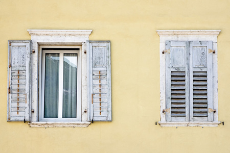 Two windows with window shutters in a yellow houseの写真素材