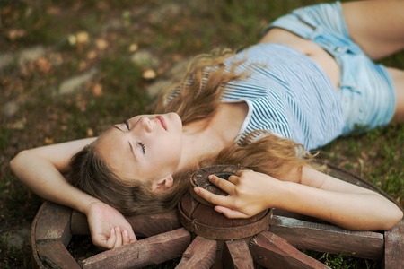A girl lying on a wooden wheel in the gardenの写真素材