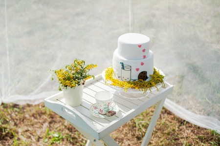 Funny wedding cake from mastic with a cup of milk and cookies. White wedding cake with flowers.の写真素材