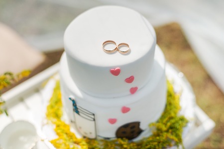 Funny wedding cake from mastic with a cup of milk and cookies. White wedding cake with flowers.の写真素材