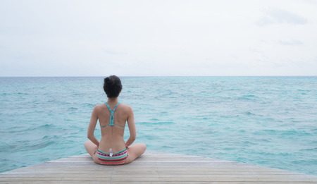 yoga on clear blue ocean in maldivesの写真素材