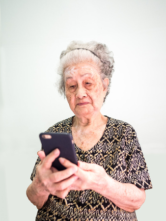 Old Asian woman reads the message and play social on the phoneの写真素材