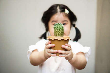 2 years old girl is holding a small pot of cactusの写真素材