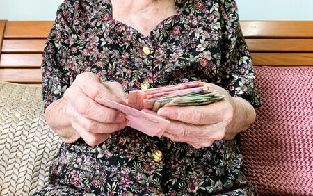 Senior retiree counting cash on her hand, Thai baht bank note. Concept for financial freedom.の写真素材