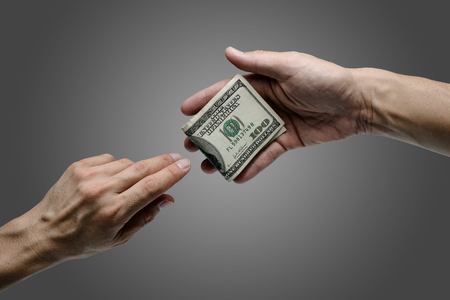 one hand offer one hundred dollar bill to otherの写真素材