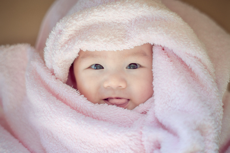 3 months old baby girl smiling face wrapped in bathing towelの写真素材