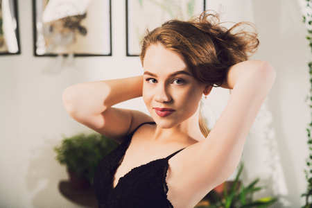 Attractive young woman with sexy red lips looking in camera touching her heirs by her handsの写真素材