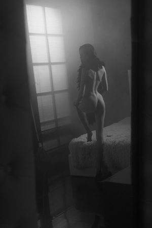 Sexy young woman staying naked or nude before her bed looking on magick moonlight falling into her window and getting ready to Helloween party. Shot trough mirror.の写真素材