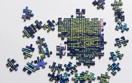 Fragment of a folded colorful jigsaw puzzle and a pile of uncombed puzzle elements against the white...