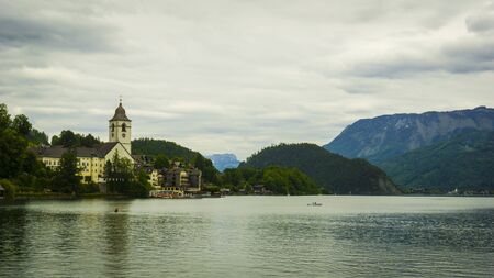 Beautiful Alps landscape with big lake,  green mountains, valley, forest and church on the Coast