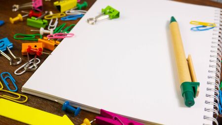 Different tools used at an office. School stationery on brown wooden table: multi-colored pencils,...