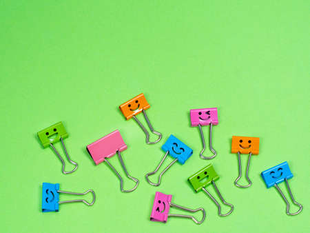 Funny smile metal binder clip or multicolored paperclip on green background with copyspace for textの写真素材