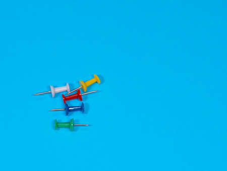 Color push pins on blue background for copyspace. Concept of office administrator business,...