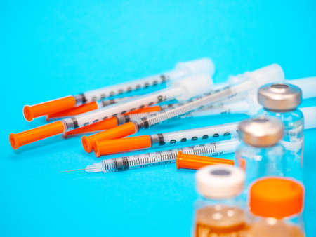 Insulin vial and syringe on blue background. Health care, doctor, clinic or hospital, medical concept. World diabetes day. Ready for vaccine injection. Pain treatment, illegal use, vaccinationの写真素材