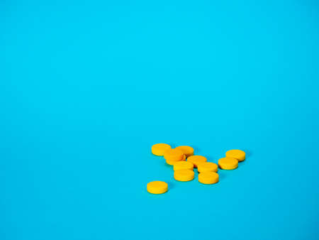 Yellow pills on blue background with copy space for text. Healthy and medicine. Pain management....