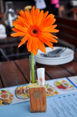 Orange gerbera in vase on the table, dining in restaurant の写真素材