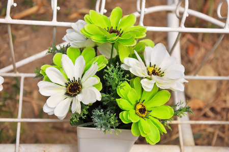 Green and white plastic flowers in a vase.の写真素材