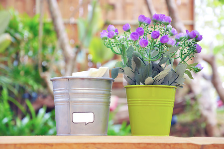 Tiny purple flowers in small bucket placed near the napkins bucket.の写真素材