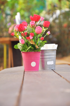 Small pink flowers in small bucket placed near the tank and napkins.の写真素材