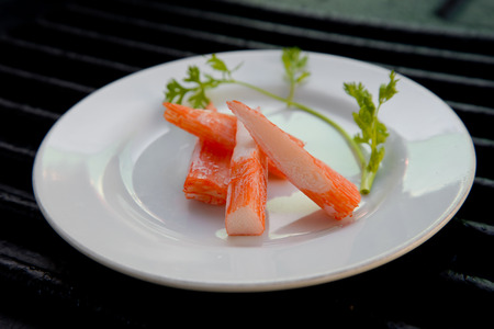 Surimi on a black plate decorated with parsley.の写真素材