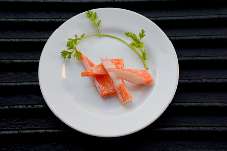 Surimi on a black plate decorated with parsley.の写真素材