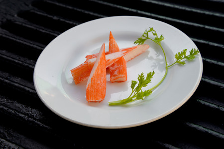 Surimi on a black plate decorated with parsley.の写真素材