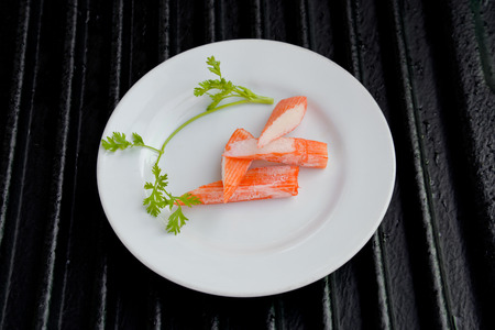 Surimi on a black plate decorated with parsley.の写真素材