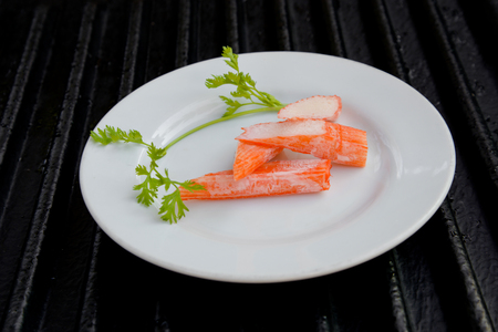 Surimi on a black plate decorated with parsley.の写真素材