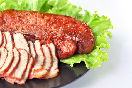 Roasted red pork on a green salad in a black plate.の写真素材