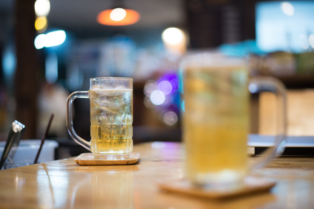 Beer in a glass on a bar under the bokeh light.の写真素材