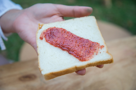 Spread the bread with strawberry jam using a spoon.の写真素材