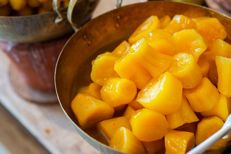 Sweet potato in syrup in brass pan