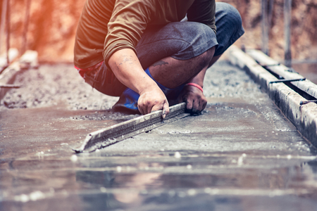 Workers are adjusting the concrete surface smooth under sunlilight.の写真素材